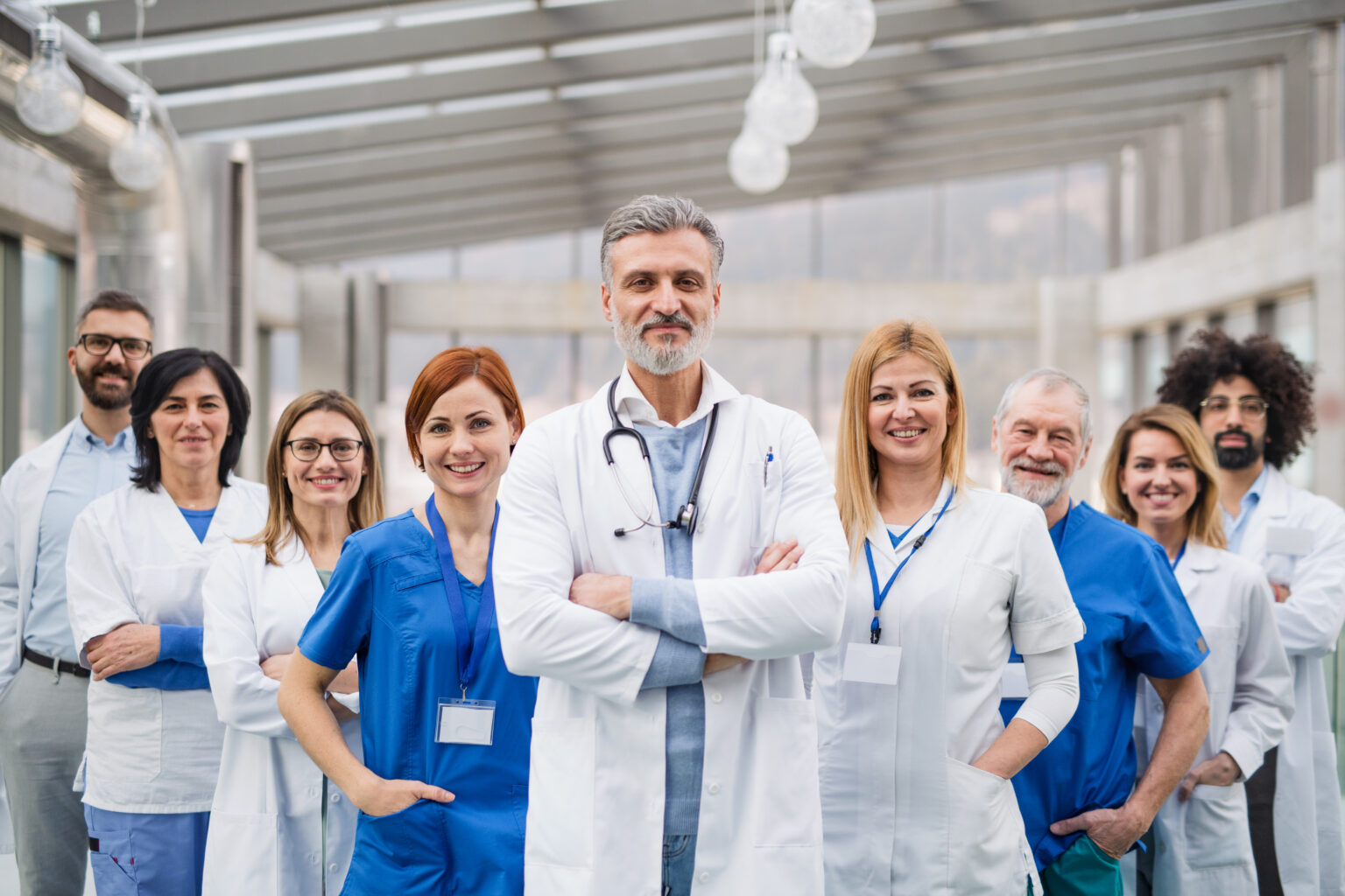 A group of doctors standing in hospital corridor on medical conference, looking at camera.