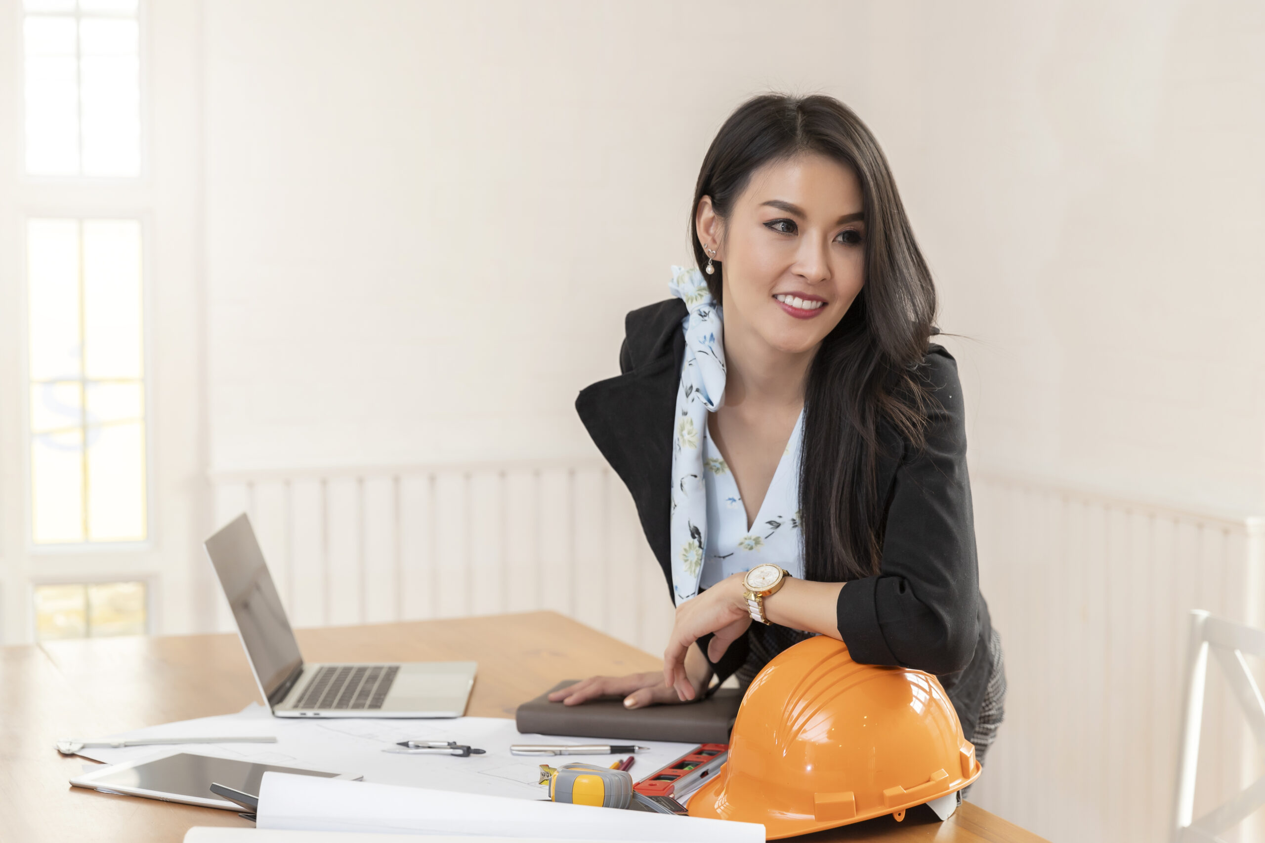 Female architect working standing at her desk with blueprint architects project in vintage office.