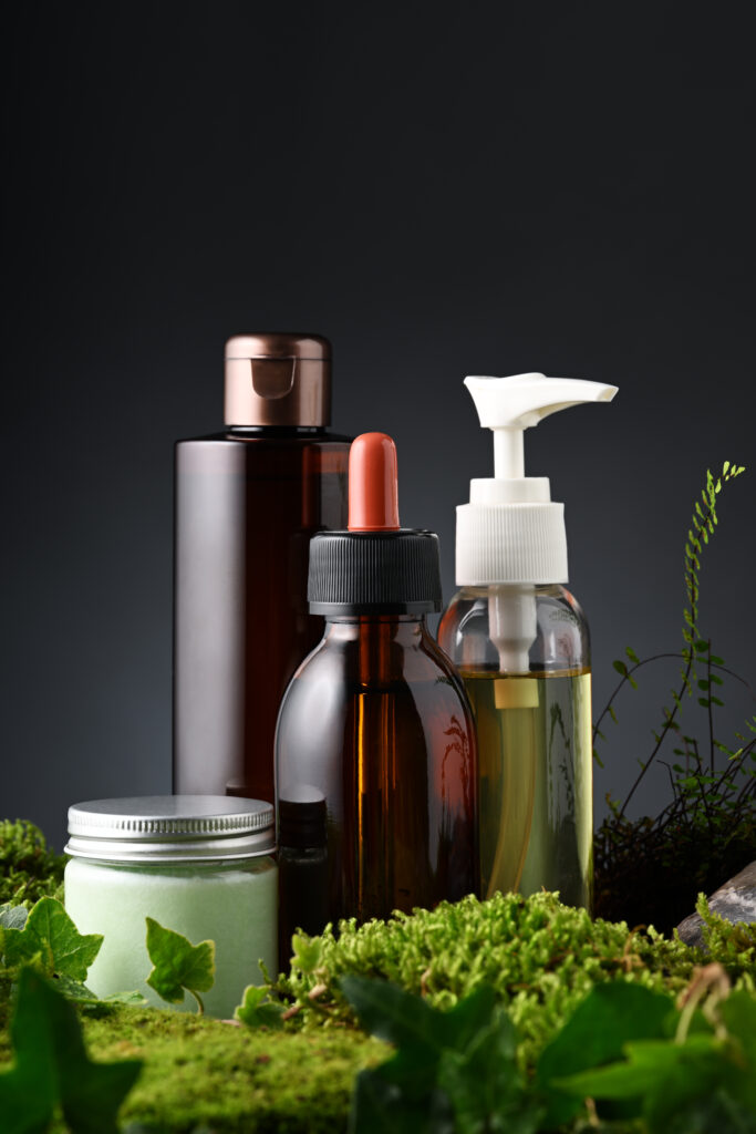 Group of skin care products with moss and leaves on black background