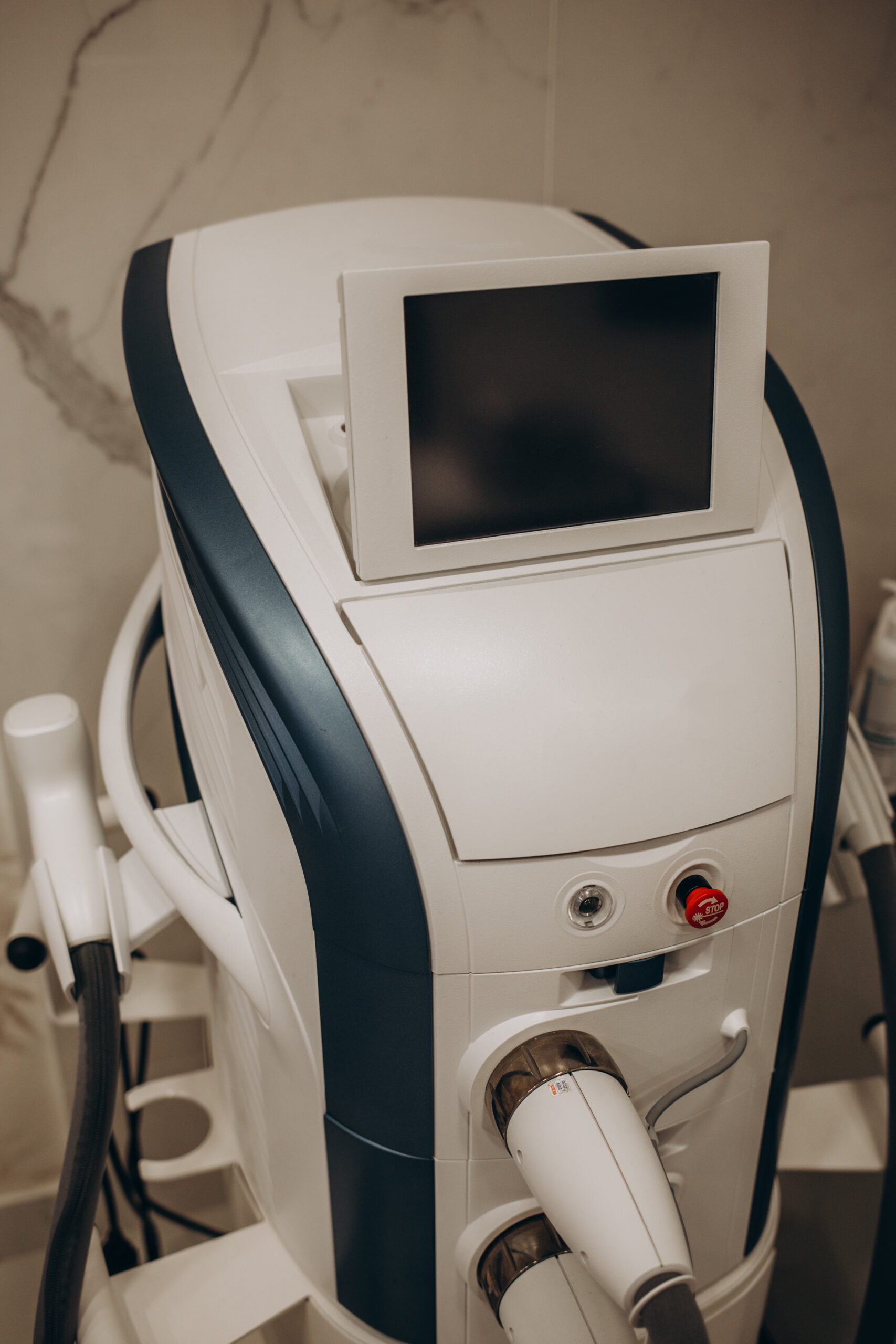 Aesthetic body treatment. Close up back side portrait of cosmetologist adjusting settings on monitor for laser hair removal device while young woman lying on couch.