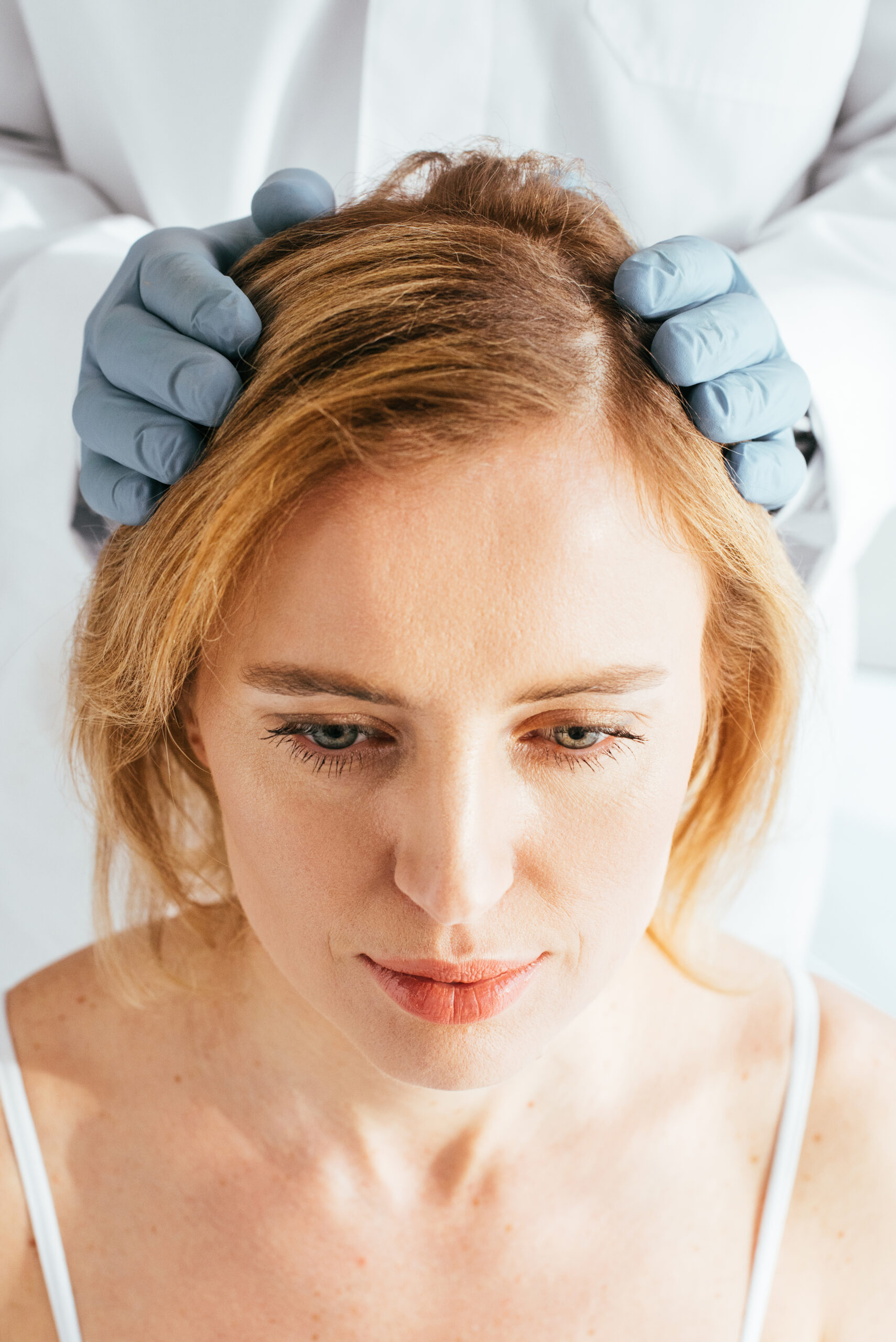 cropped view of dermatologist in latex gloves examining hair of patient
